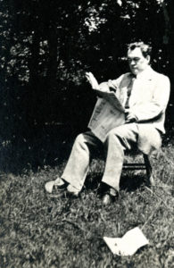 Cabell sitting in chair reading the newspaper outside
